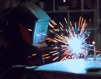 manufacturing welder in welding mask sparking